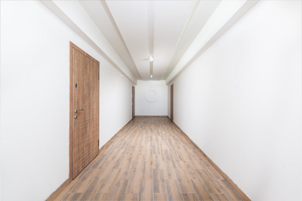 Clean white hallway with wooden flooring and contemporary doors, showcasing minimalism.
